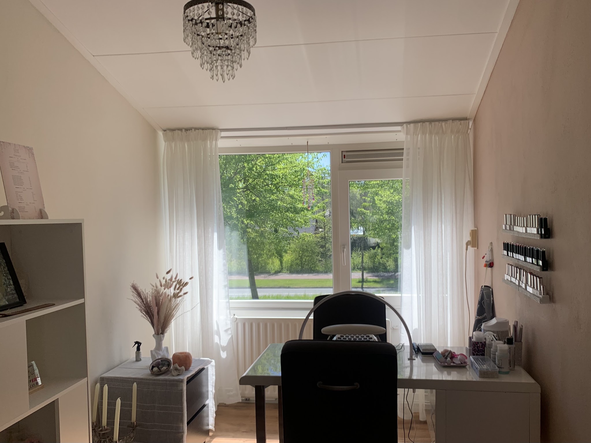 De studio: een lichte kamer met kroonluchter, nageltafel, stoel en een groot raam